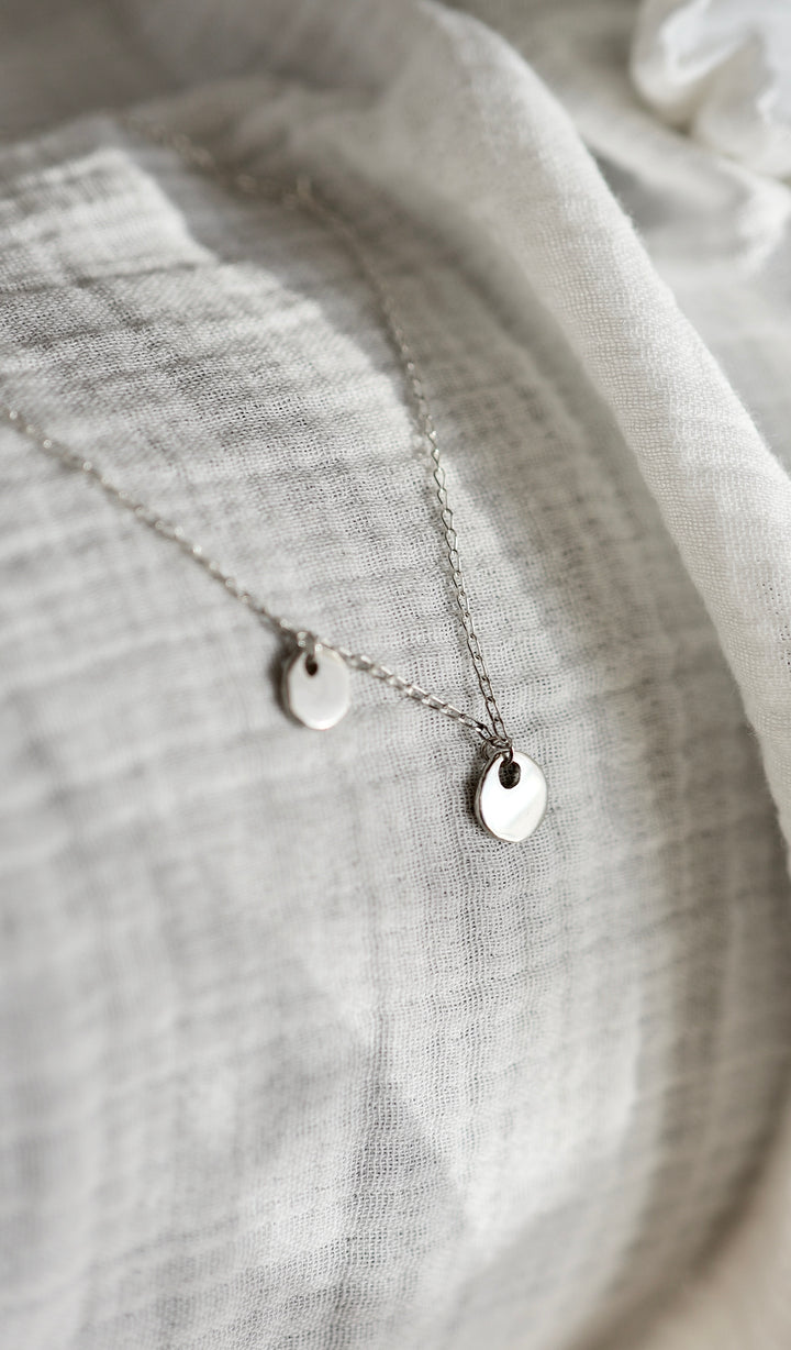 Handcrafted silver organic coin pendant necklace by Atelier Objectora, featuring a irregular medallion design, timeless and versatile

 Ručne vyrobený strieborný náhrdelník s organickým okrúhlym príveskom od Atelier Objectora, s nepravidelným medailónom, nadčasový a univerzálny